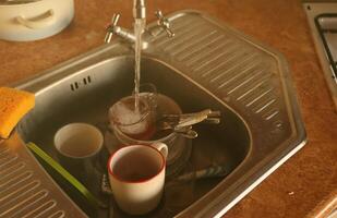 Stack of dirty dishes with food leftovers in the kitchen sink. Unwashed dishes photo