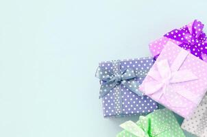 Pile of a small colored gift boxes with ribbons lies on a violet background. Minimalism flat lay top view photo