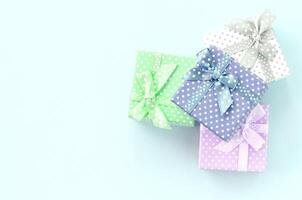 Pile of a small colored gift boxes with ribbons lies on a violet background. Minimalism flat lay top view photo