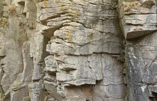 Light coarse natural rock stone background. Mining cliff rough front surface. Big limestone stack backdrop. Heavy grunge damaged granite block texture photo