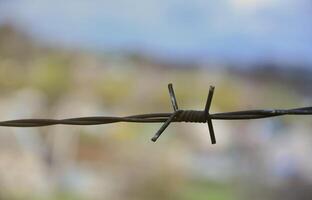 Macro shot of an element of old and rusty barbed wire with a blurred background. Fragment of a village fence of a territorial site photo