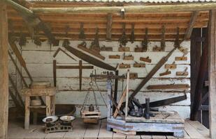 Collection of planers and retro wood saws hang on a wooden wall near an old house. Carpenters plane and other things on wall photo