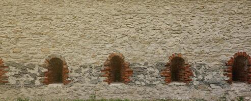 Very old window in brick stone wall of castle or fortress of 18th century. Full frame wall with window photo