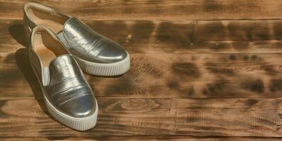 Original shiny shoes in disco style lie on a vintage wooden surface made from fried brown boards. Fashionable clothing retro accessory for discos and parties in the style of the eighties photo