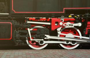 Wheels of the old black steam locomotive of Soviet times. The side of the locomotive with elements of the rotating technology of old trains photo