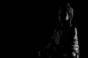 Buddha Purnima and Vesak day concept, Grey Buddha statue with low key light against deep black background photo