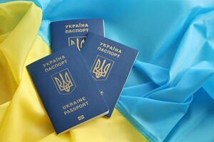 Three Ukrainian biometrical passports on folded waving flag of Ukraine country photo