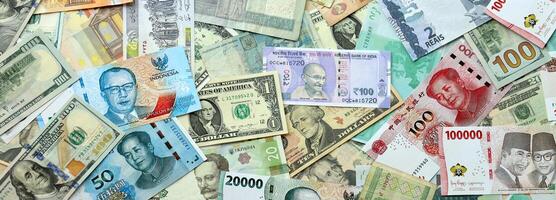 Many banknotes of different currency. Background of big amount of random money bills photo