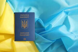 One Ukrainian biometrical passport on folded waving flag of Ukraine country photo