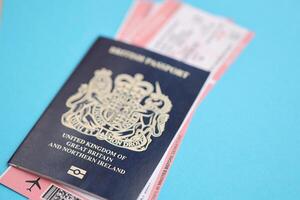 Blue British passport with airline tickets on blue background close up photo