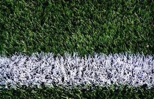 White stripe on a bright green artificial grass soccer field photo