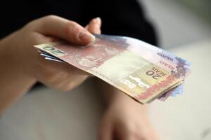 Brazilian money bills in woman hand. Female gives bunch of brazilian reais to us photo