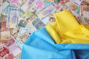 Ukrainian flag on many banknotes of different currency. Background of war funding photo