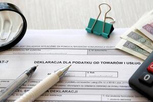 Declaration for tax on goods and services VAT-7 form on accountant table with pen and polish zloty money bills photo