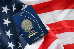 Blue Brazilian passport on United States national flag background close up photo