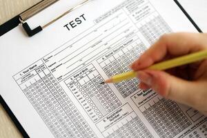 Female student hands testing in exercise and taking fill in exam paper sheet with pencil at school test photo