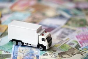 Delivery truck on many banknotes of different currency. Background of trucking or moving concept photo