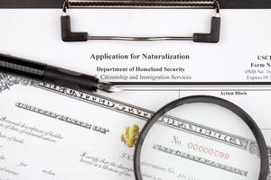 n-400 solicitud para naturalización y certificado de naturalización en a4 tableta mentiras en oficina mesa con bolígrafo y aumentador vaso foto