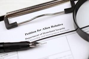 I-130 Petition for alien relative blank form on A4 tablet lies on office table with pen and magnifying glass photo