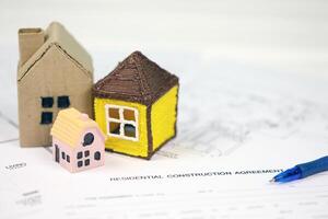 Residential construction agreement ready to sign with small toy houses and pen. Construction contract photo