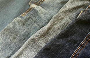 Many jeans in stack in wardrobe room. Row of pants denim jeans in closet. Concept of buy, sell, shopping and fashionable clothes photo