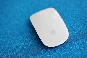 KYIV, UKRAINE - NOVEMBER 27, 2023 Apple Magic Mouse 3rd generation lies on sparkling glitter surface photo