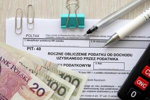 Annual calculation of tax on income obtained by taxpayer, PIT-40 tax forms on accountant table with pen and polish zloty money bills photo