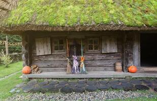 Three different brooms of witches stand at the old wooden hut house photo