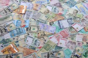 Many banknotes of different currency. Background of big amount of random money bills photo