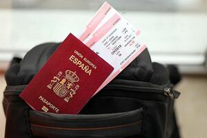 Red Spanish passport of European Union with airline tickets on touristic backpack photo