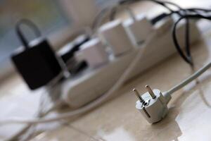 Overloaded power boards. Power strips with different electrical plugs on white floor photo