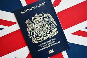 Blue British passport on national flag background close up photo