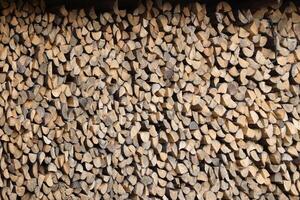 Firewood stacked near the wooden wall of old hut. Many chopped logs of firewood photo