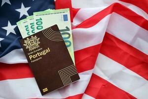 Red Portugal passport of European Union and money on United States national flag background photo