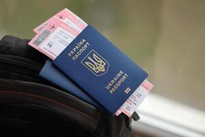 Two ukrainian biometrical passports with air flight tickets on black touristic backpack photo