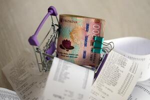 Ukrainian hryvnias money bills bunch in shopping trolley surrounded by many paper receipts photo