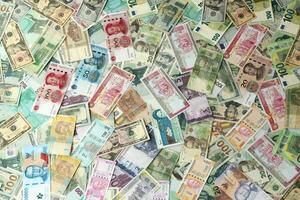 Many banknotes of different currency. Background of big amount of random money bills photo