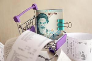 Iranian rials money bills bunch in shopping trolley surrounded by many paper receipts photo