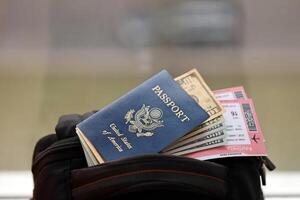 Blue United States of America passport with money and airline tickets on touristic backpack photo