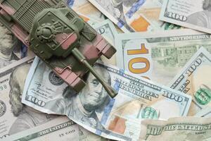 Tank on crumpled hundred dollar bills banknotes. Background of war funding and military support photo