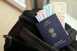 Blue Indian passport with money and airline tickets on touristic backpack photo