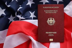 Red German passport of European Union on United States national flag background close up photo