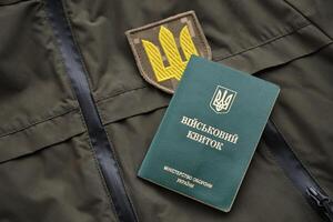 Military token or army ID ticket lies on green ukrainian military uniform photo