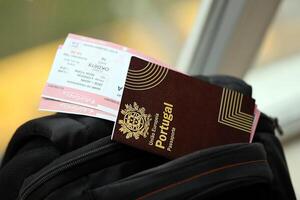 Red Portugal passport of European Union with airline tickets on touristic backpack photo