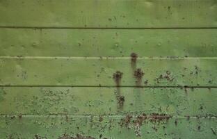 Texture of an old green metal wall with significant damage from exposure to unfavorable weather conditions and dampness photo