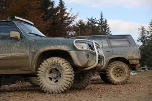 Automobile in a countryside landscape with a mud road. Off-road 4x4 suv automobile with ditry body after drive in muddy road photo