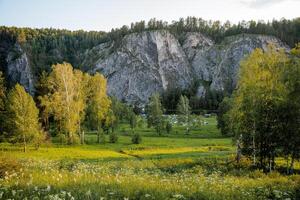 Beautiful lighting from the sunlight at sunset for, the rays of the sun illuminate the green glade, the lawn in front of the rock, the landscape in the countryside. photo