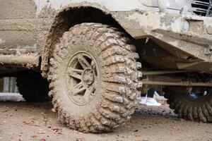 Wheel closeup in a countryside landscape with a mud road. Off-road 4x4 suv automobile with ditry body after drive in muddy road photo