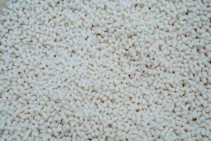 Granules of polymer plastic of white color, petrochemical production of plastics, a bunch of crystalline debris, round tubes are cut finely. photo