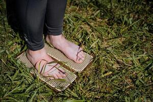 The girl stands with her bare feet on nails, the practice of meditation and fortitude, sharp metal nails, willpower. photo